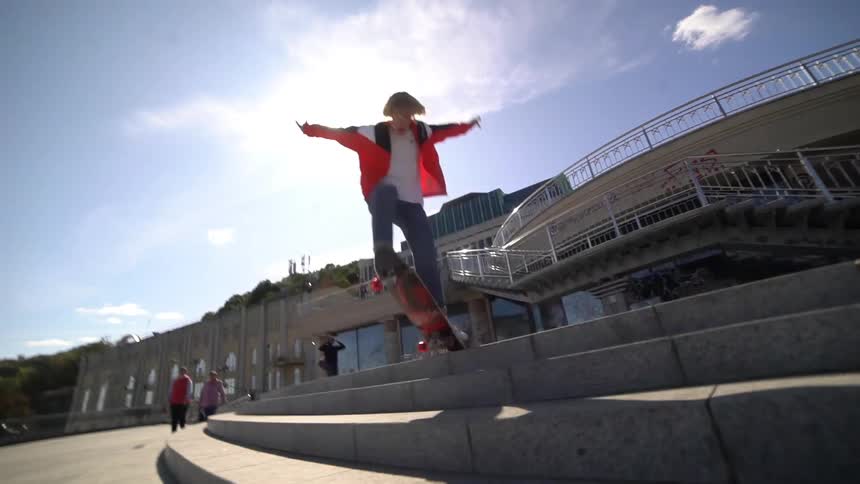 Skateboarder jumps down outdoor steps on his skateboard on a sunny day