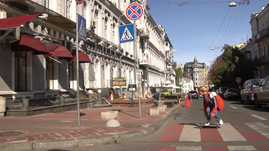 A skateboarder rides across a crosswalk in front of a europeanstyle building