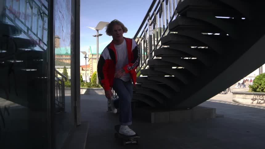 A boy on a skateboard between stairs and a building