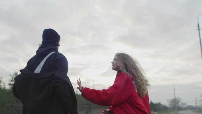 Young woman and man arguing with each other on the side of a highway