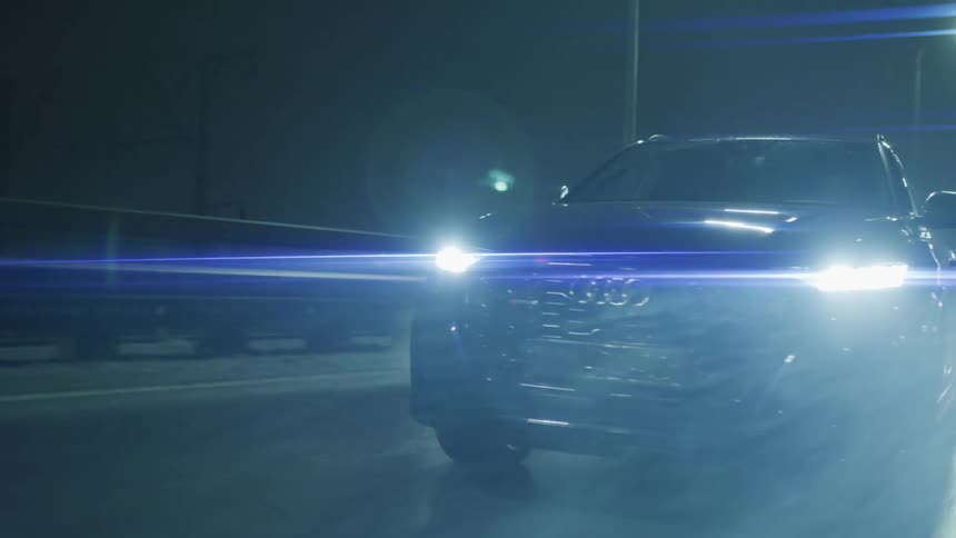 A car is driving in the rain at night