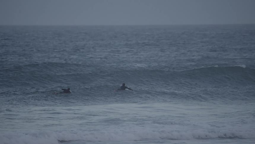 Two surfers in the ocean waiting for waves at early morning or late evening hours