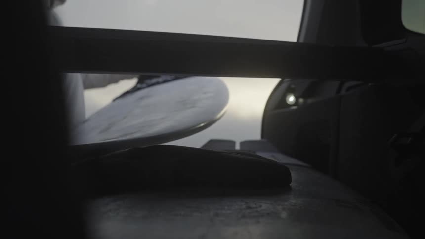 Close up of a person taking a surfboard out of a vehicle