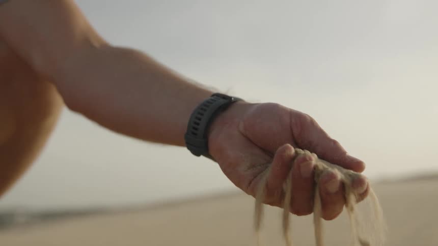 Hand picking up sand and releasing it