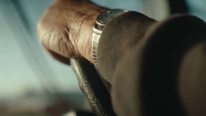 Hand of a person with a watch on his wrist driving an agricultural machine