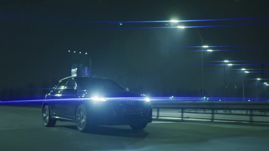 Audi car moving on a highway at night illuminated by streetlights and headlights