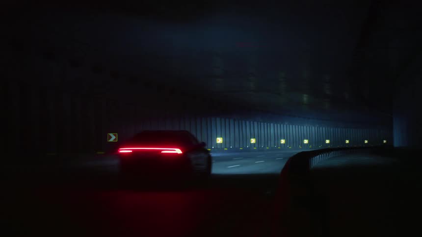 A car driving through a dark tunnel illuminating the interior with its headlights