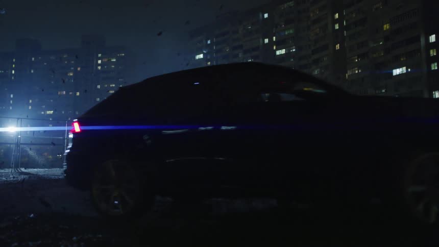 Sports car making a turn next to residential buildings in the city at night