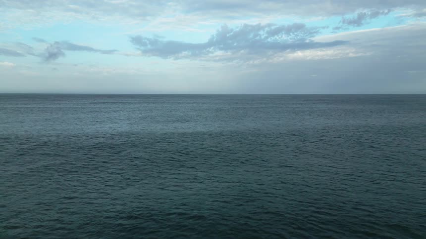 Aerial view of the ocean going backwards under a blue sky