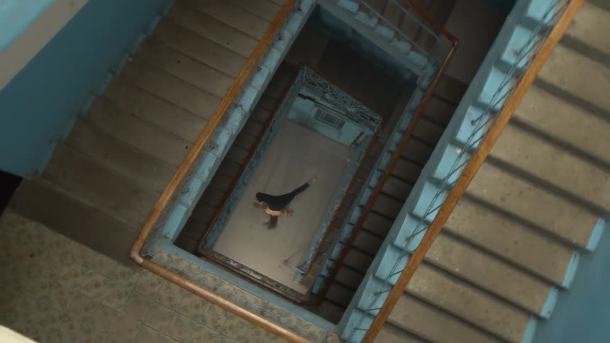 A man breakdancing at the bottom of a staircase