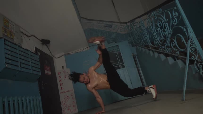 Young man dancing break dance next to a staircase