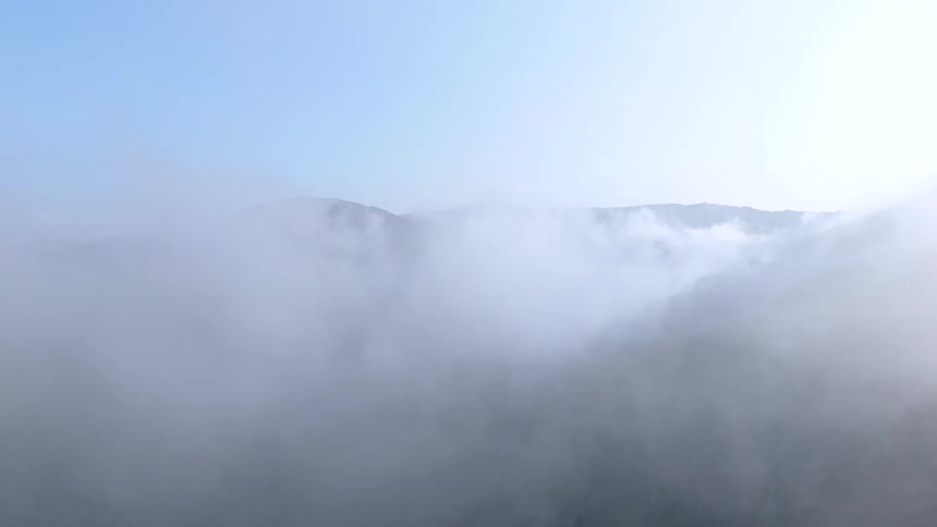 Aerial view of a mountain range under a layer of clouds