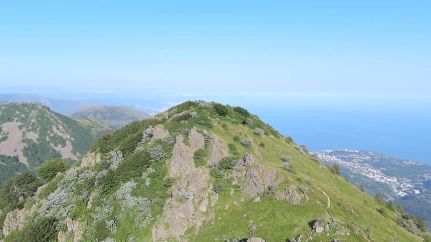Panorama of large mountains with vegetation and the sea in the background