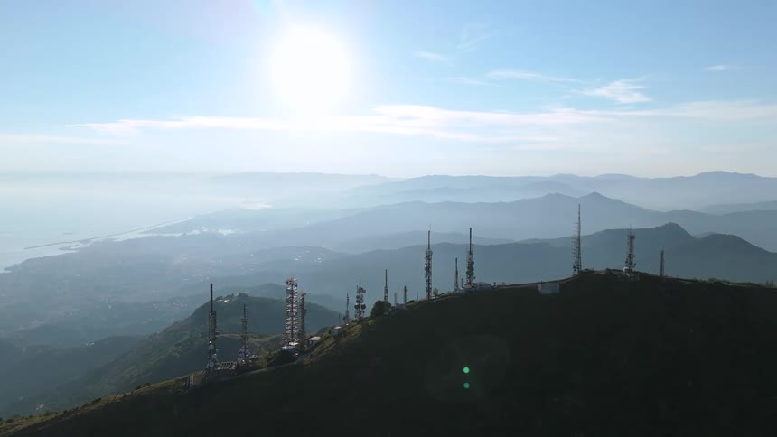 Several cell towers on top of a mountain peak