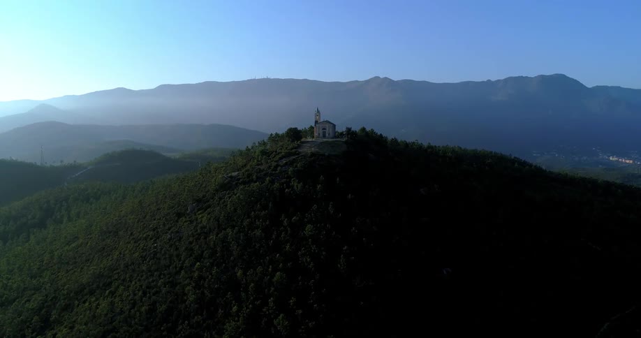 Church on top of a hill surrounded by green mountains