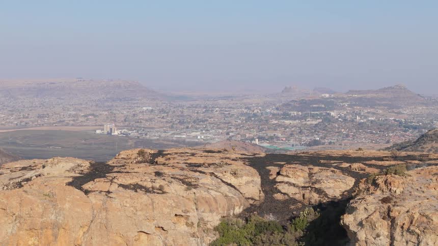 Aerial panorama of rocky mountains with a city in the background