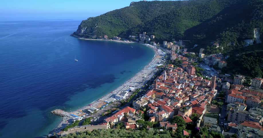 A picturesque coastal city skyline nestled between a lush mountainside and a crystal clear blue sea