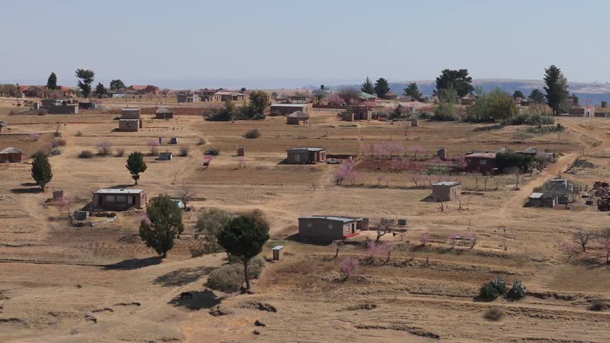 A dry rural neighborhood with trees scattered throughout