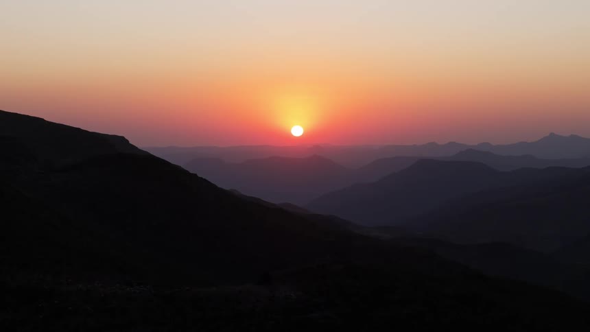 Landscape of orange sunrise on horizon and view of silhouette of mountains