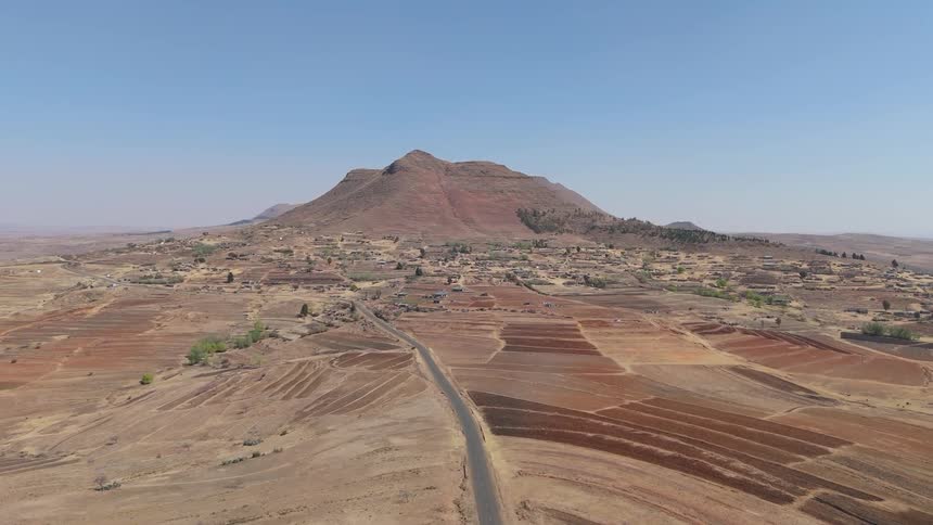 Aerial view of a highway in arid terrain with canyons in the background