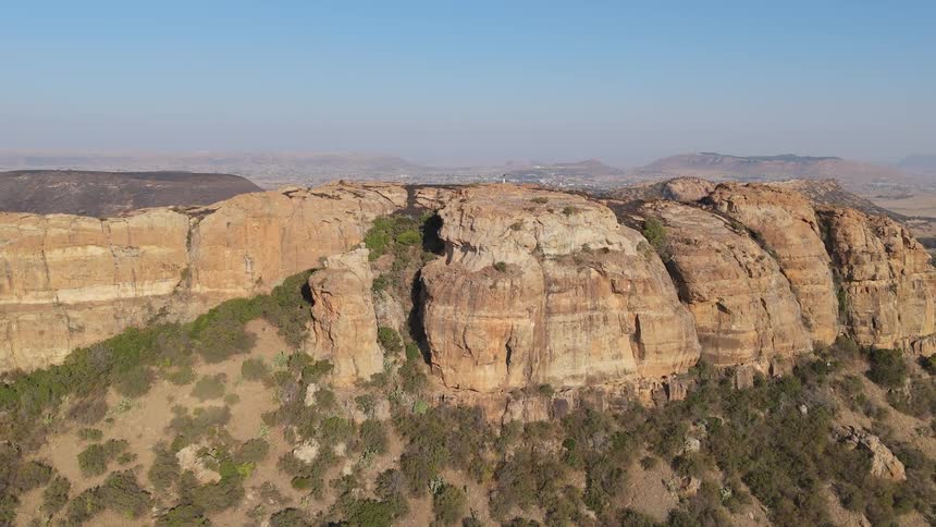 Stone hills and mountains surround a large town located in arid terrain