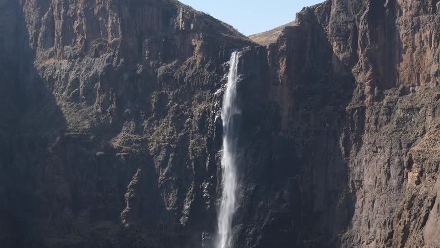 A tall waterfall cascades down a steep rocky cliff face