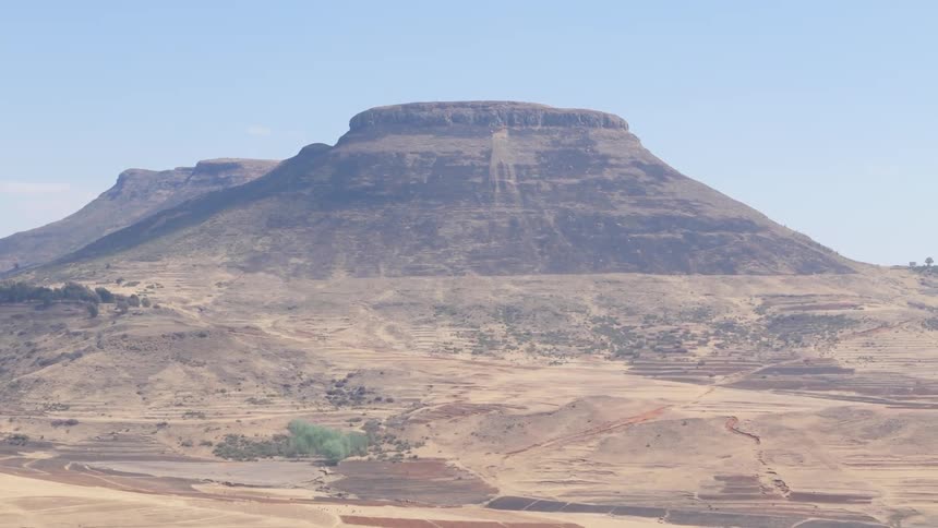 Aerial panorama of a large barren mountain against a blue sky