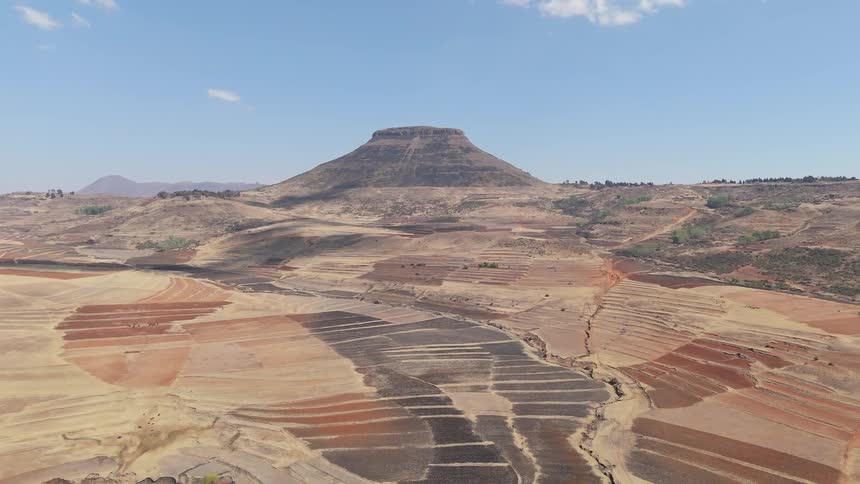 Aerial view of a vast arid terraced landscape with a flat topped mountain in the horizon