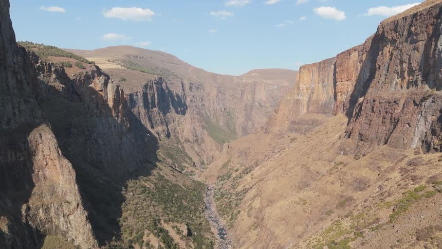 A vast canyon with steep rugged cliffs and a narrow valley