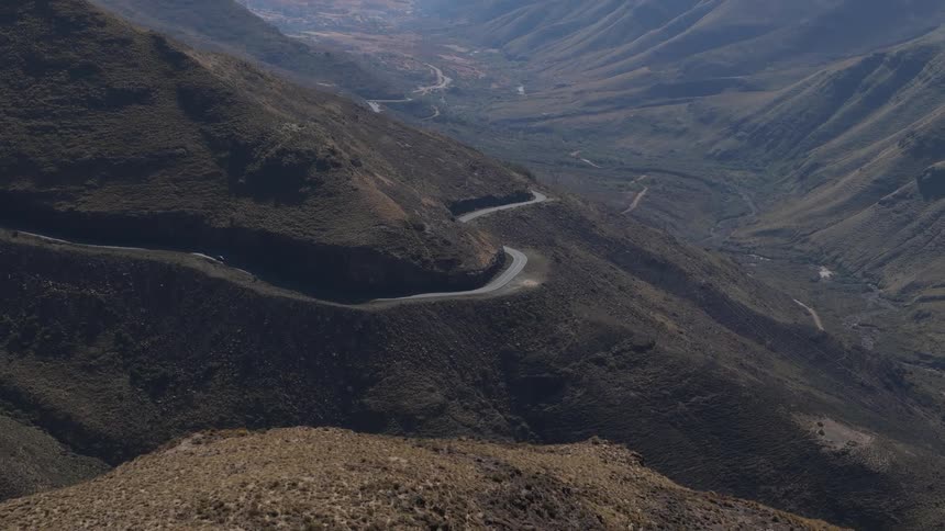 A winding road cutting through a brown mountainous terrain