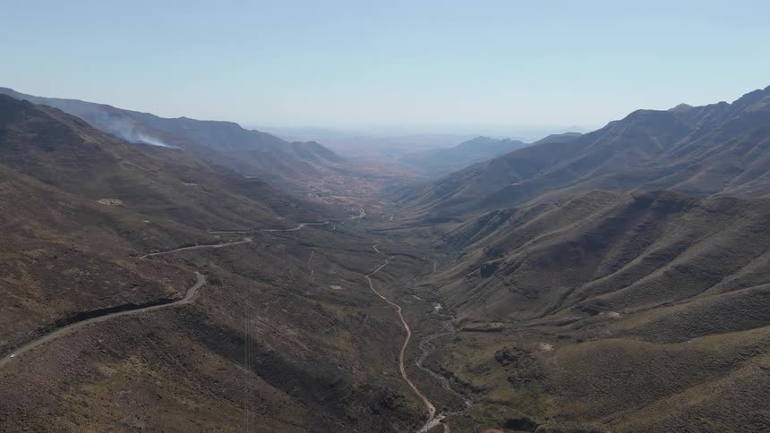 A vast mountainous landscape with a winding road snaking through the valleys