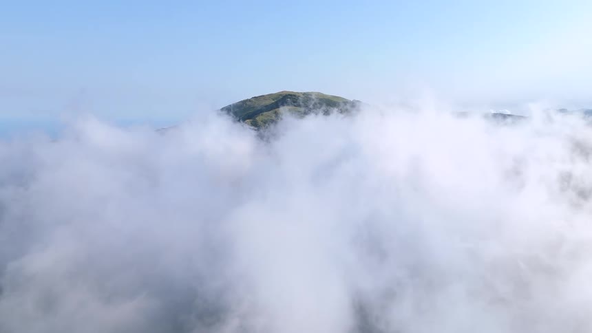 Aerial view of a cloud layer surrounding a mountain