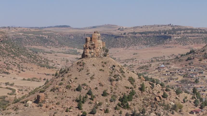 A small rural town in a desert sits near a prominent rock formation