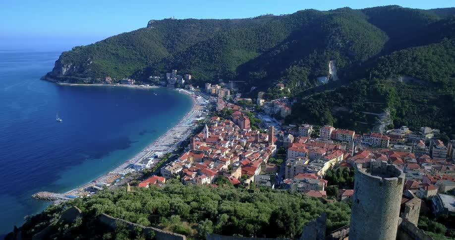 Aerial view of a seaside town surrounded by forested mountains