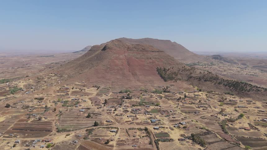 Aerial panorama of a village built in a desert region with canyons in a mountain valley on the horizon