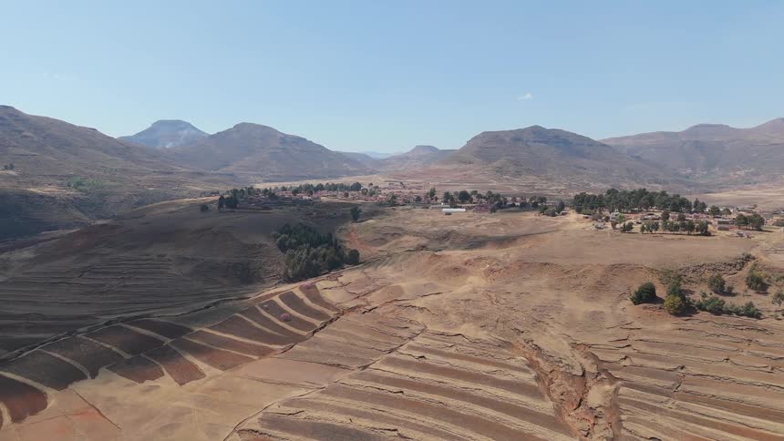 Aerial view of a rocky terrain with a village and mountains in the background