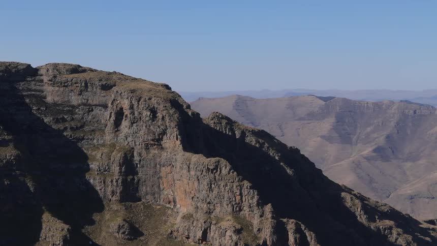 Scenery is aerial of a valley mountains with cliffs on a blue sky day