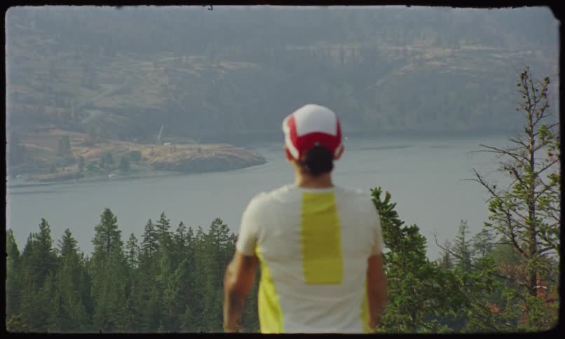 Jogger pauses briefly to look across a conifer covered slope towards the river on a foggy day