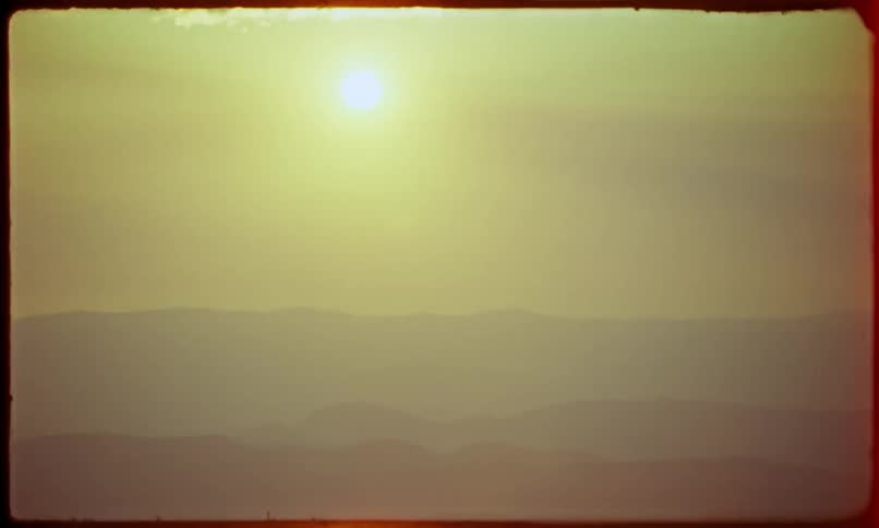 A serene sunrise over hills or mountains captured on vintage film