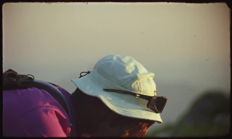 Man in white hat outdoors washing his face