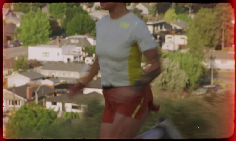 Woman running in a natural environment on a hill with houses in the background