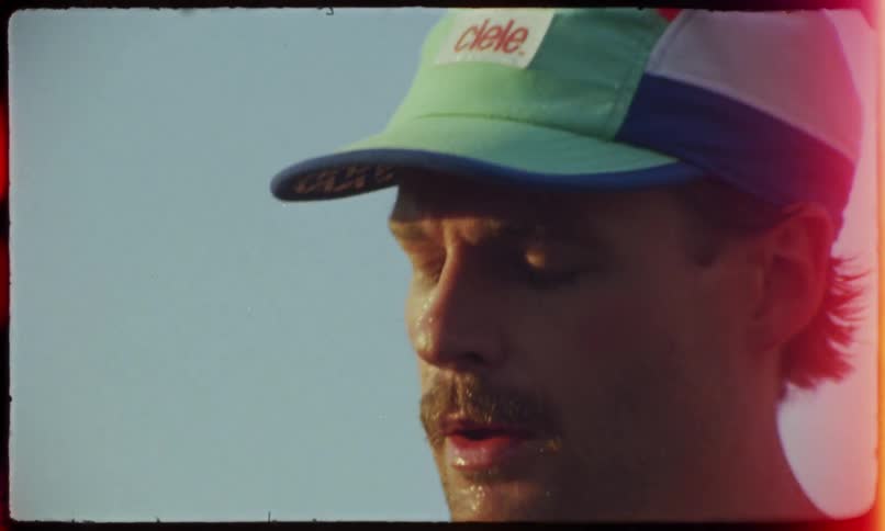 A face of a man wearing a cap and he is sweating and he passes his hand over his forehead to remove the sweat