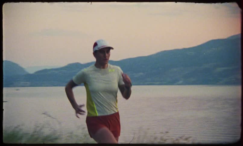 A woman in workout clothes jogs on a path by a lake