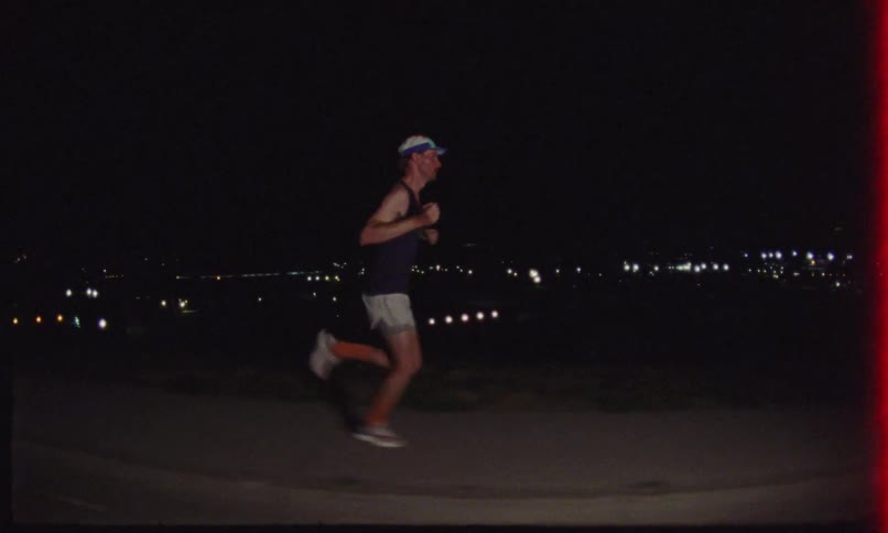 Man in cap and tank top running at night
