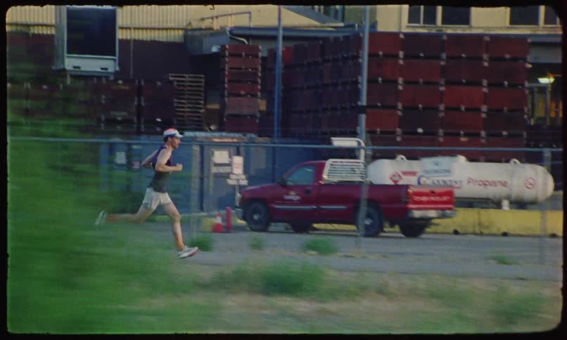 A male jogger runs past a bicyclist and a distribution facility
