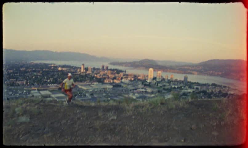 A woman running up a hill and behind her there is a huge city