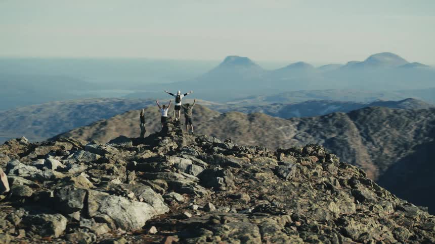 People with open arms on a rocky mountain peak
