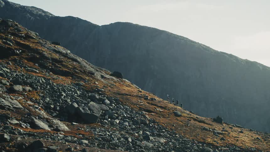 Aerial view of a group of four people hiking and climbing a large rocky mountain