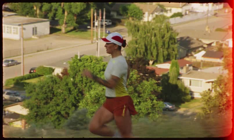 A woman runs on a path with a suburb and city with a river as a backdrop