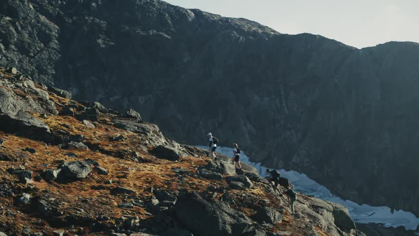 Group of hikers follows a mountain trail with rocky terrain